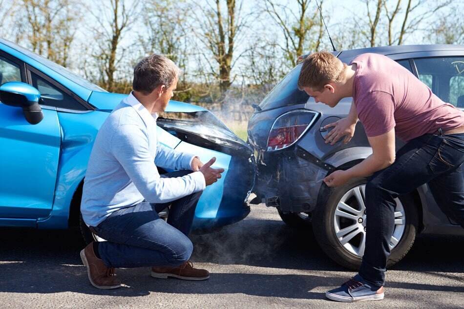 Individuals viewing cars post accident