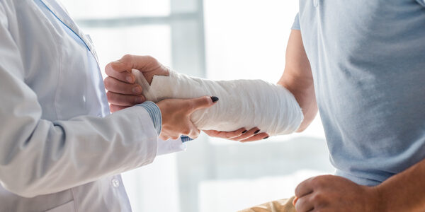 Cropped View Of Orthopedist Touching Injured Arm Of Man