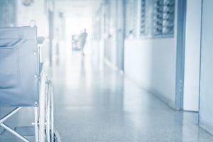 Empty wheelchair parked in hospital pathway blurred with patient walk in hospital