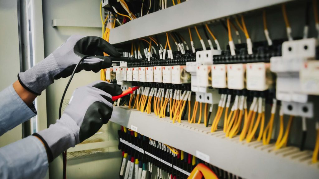 an electrician testing voltage at a circuit board