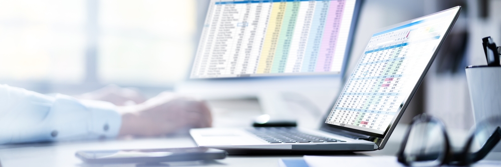 healthcare worker at desk with a computer and laptop doing Medical Coding And Billing Spreadsheets