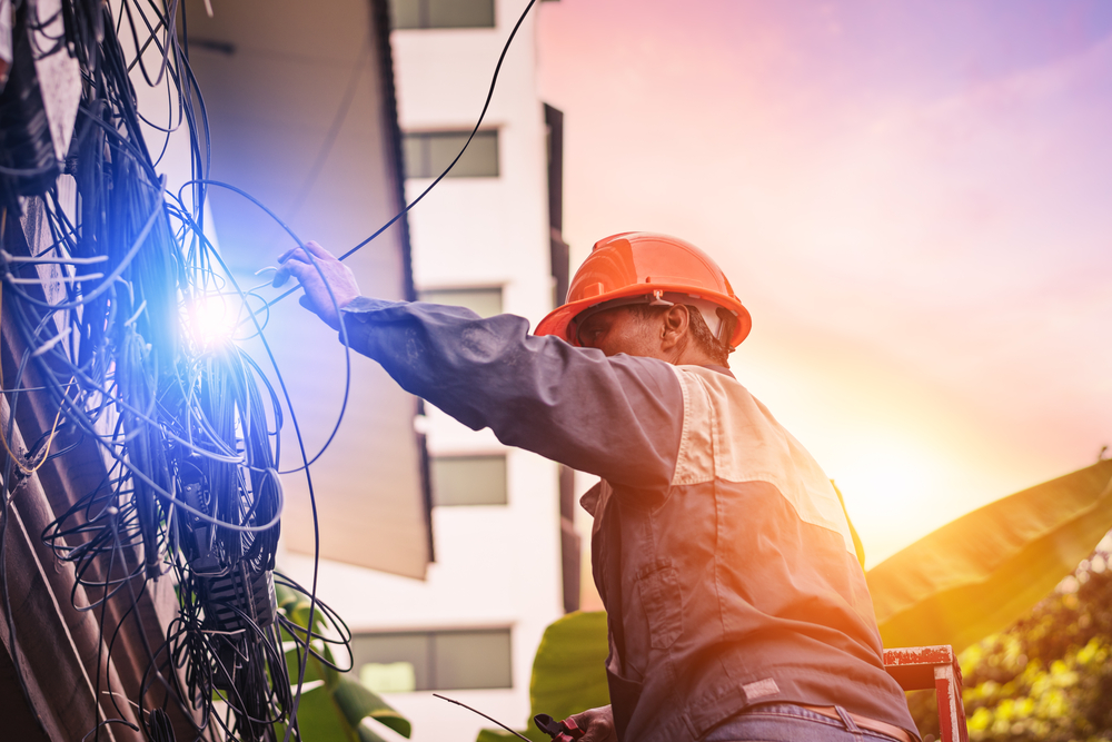 an electrician on a ladder checking wiring on an apartment