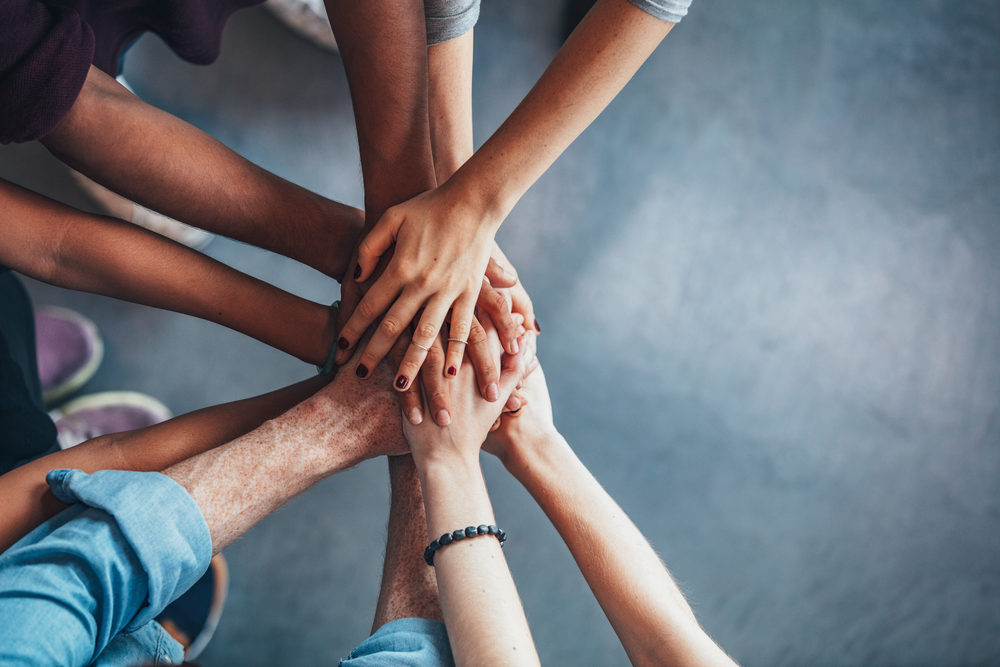 Top down view of many people putting their hands together