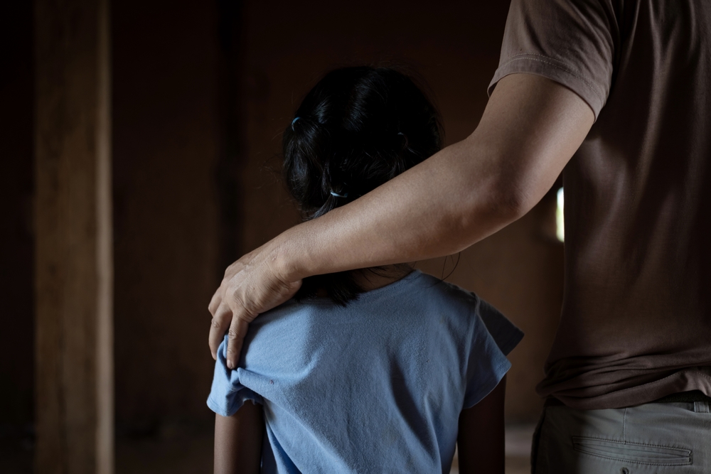 a female child victim of human trafficking held by the shoulder