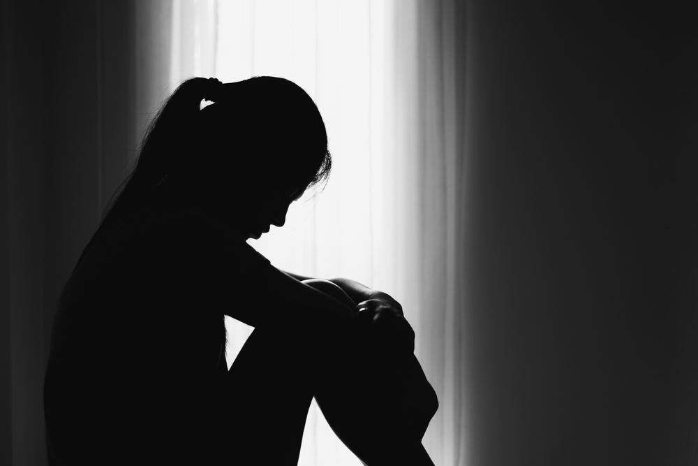 silhouette of a depressed woman sitting on the floor