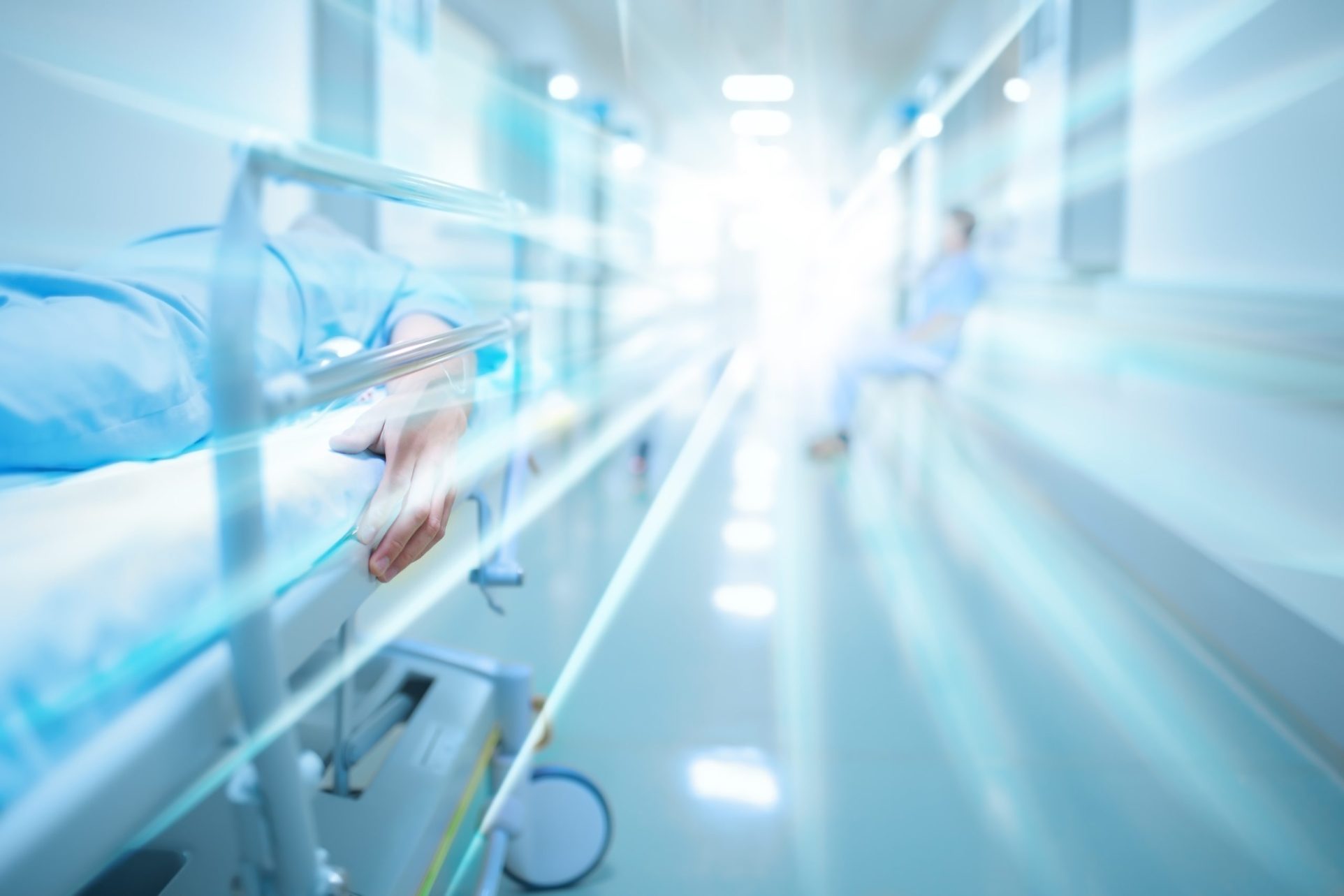Patient on a gurney in a hospital corridor with blurred light shining.