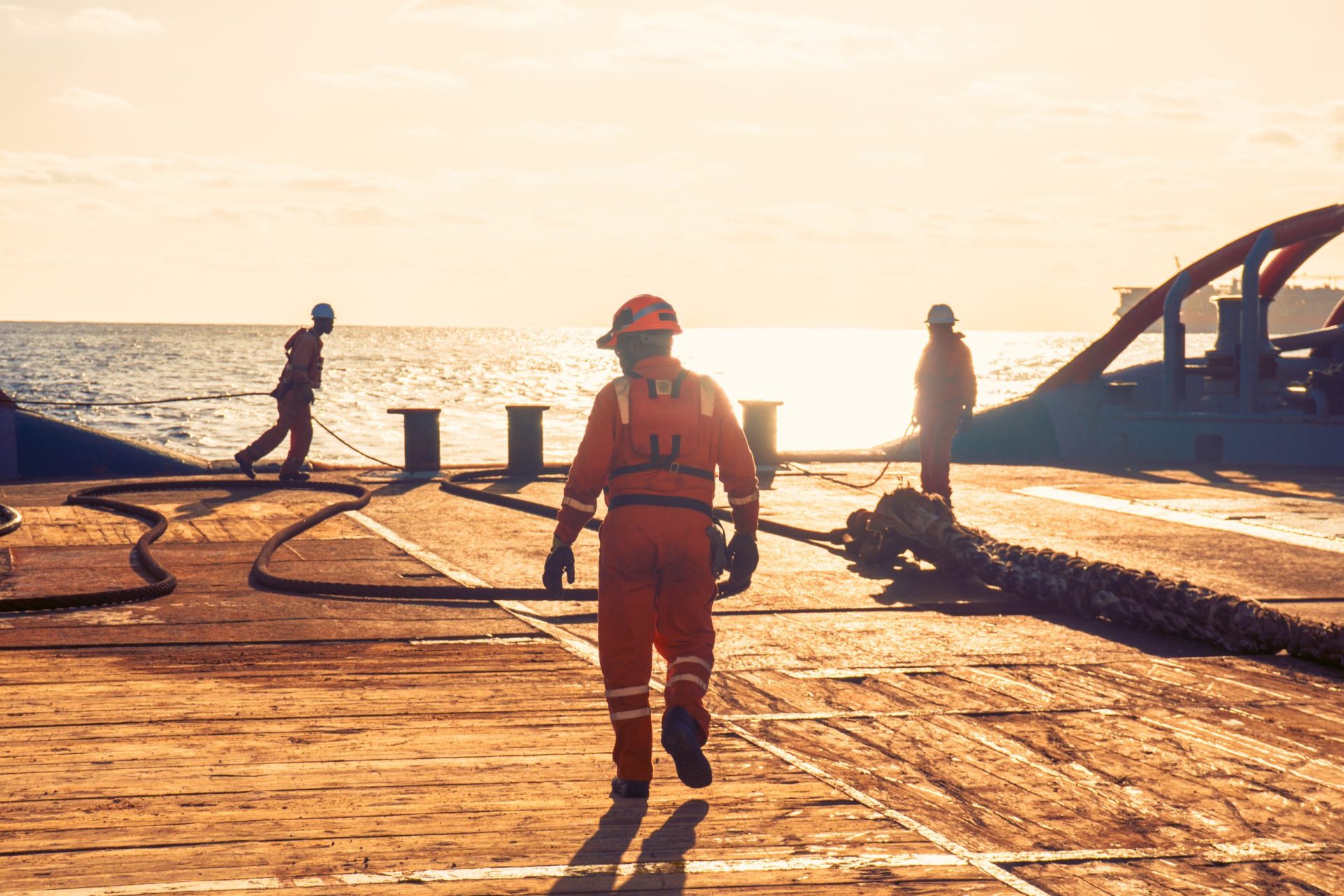 Tug boat workers on a deck at sunset.